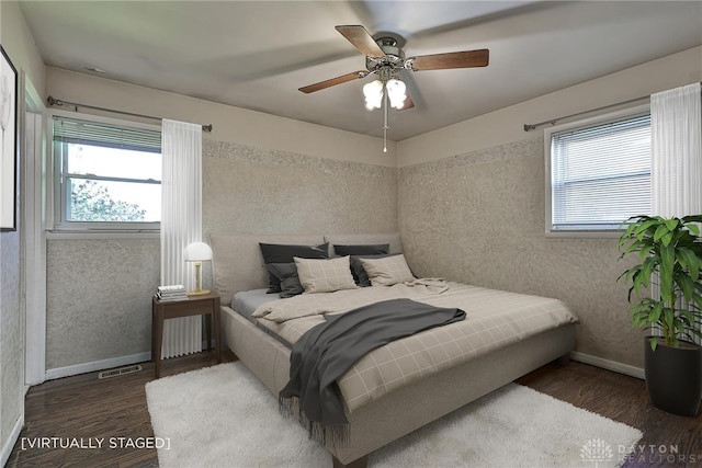 bedroom featuring baseboards, ceiling fan, wood finished floors, and visible vents