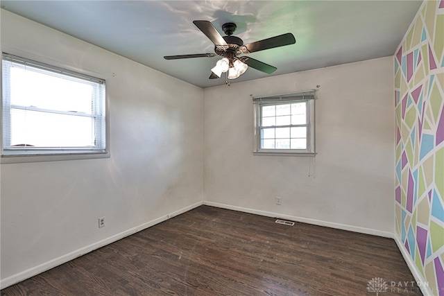 empty room with visible vents, a ceiling fan, baseboards, and wood finished floors