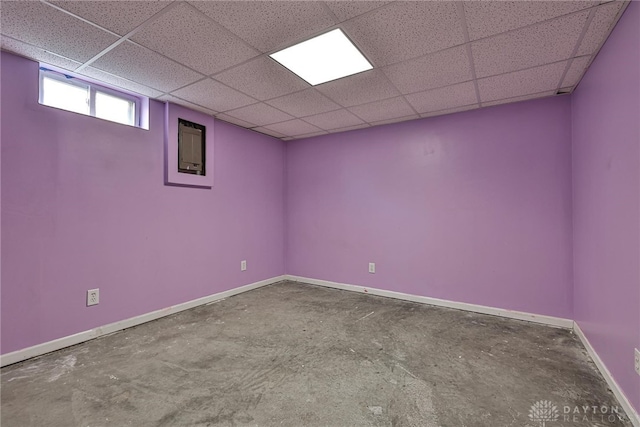 empty room with baseboards, unfinished concrete flooring, and a paneled ceiling