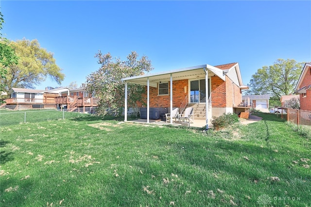 rear view of house featuring a patio, a fenced backyard, brick siding, a hot tub, and a yard