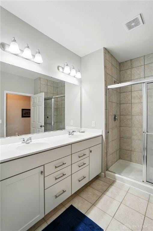 full bath with a sink, tile patterned flooring, double vanity, visible vents, and a stall shower