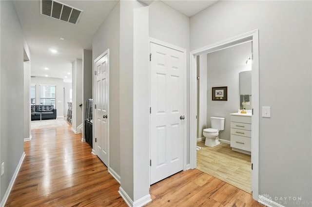 hallway featuring visible vents, recessed lighting, light wood-style flooring, and baseboards