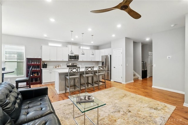 living area featuring light wood-style floors, baseboards, ceiling fan, and recessed lighting