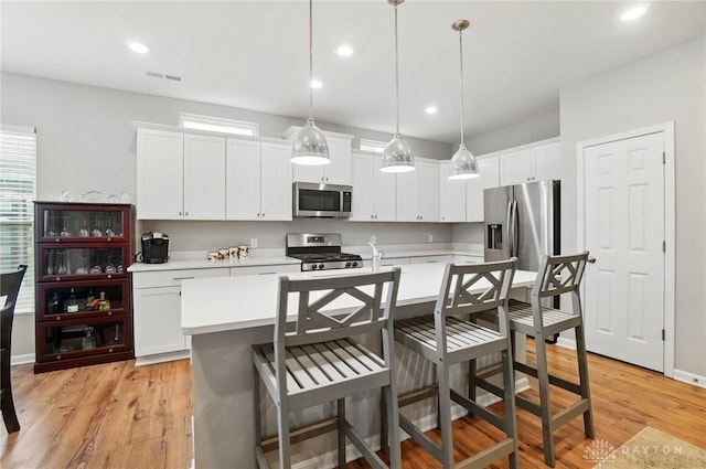 kitchen featuring light countertops, appliances with stainless steel finishes, light wood-style flooring, and an island with sink