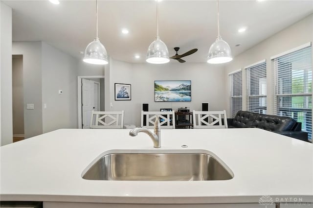 kitchen featuring light countertops, recessed lighting, open floor plan, and a sink