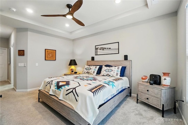 bedroom featuring light carpet, baseboards, recessed lighting, a tray ceiling, and a ceiling fan