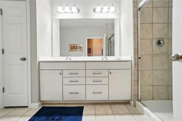 full bathroom with double vanity, a sink, tile patterned flooring, and a stall shower