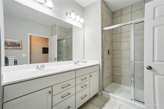 full bathroom featuring double vanity, a shower stall, a sink, and tile patterned flooring