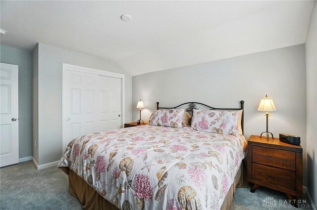 bedroom with carpet floors, baseboards, lofted ceiling, and a closet