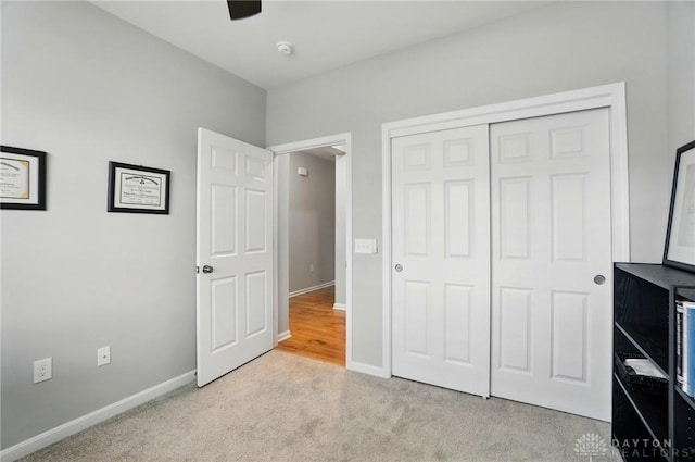unfurnished bedroom with a closet, baseboards, ceiling fan, and light carpet