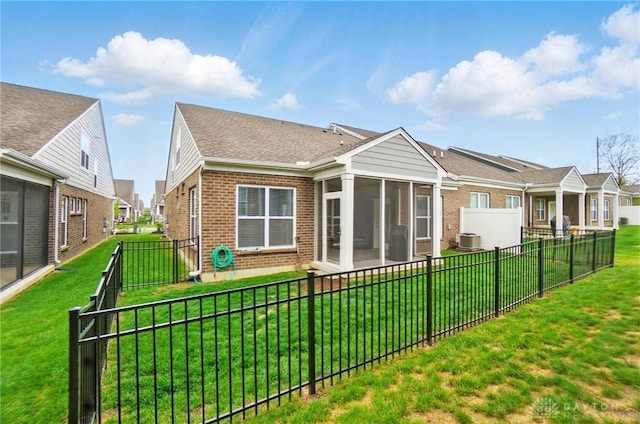 rear view of property featuring brick siding, a residential view, a fenced backyard, and a sunroom