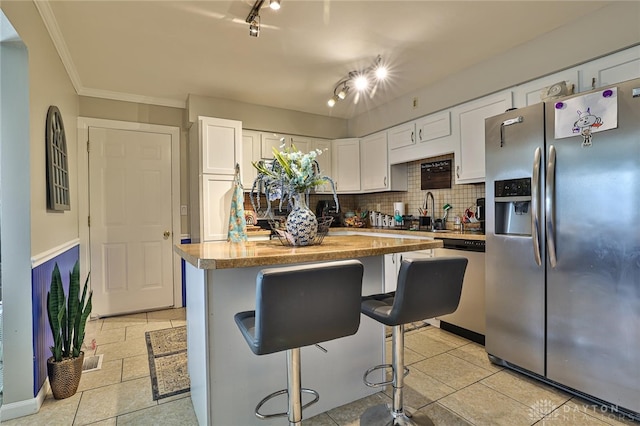 509 Hamilton Ave, New Carlisle, OH 45344 - kitchen with stainless steel appliances, white cabinets, a sink, backsplash, and a kitchen bar