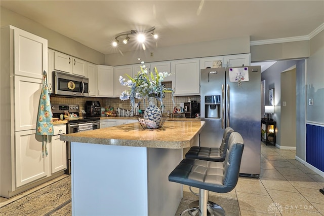 509 Hamilton Ave, New Carlisle, OH 45344 - kitchen with appliances with stainless steel finishes, backsplash, white cabinetry, a breakfast bar area, and ornamental molding
