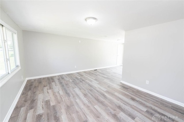 spare room with baseboards and light wood finished floors