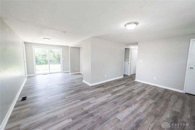 empty room featuring baseboards, visible vents, and wood finished floors