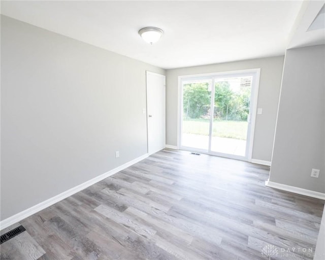 spare room featuring baseboards, wood finished floors, and visible vents