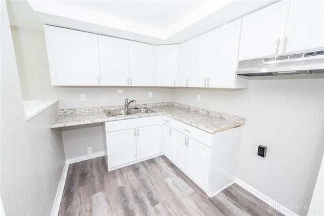 washroom featuring baseboards, a sink, and light wood-style floors