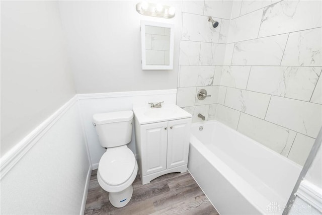 bathroom featuring toilet, tub / shower combination, wood finished floors, and vanity