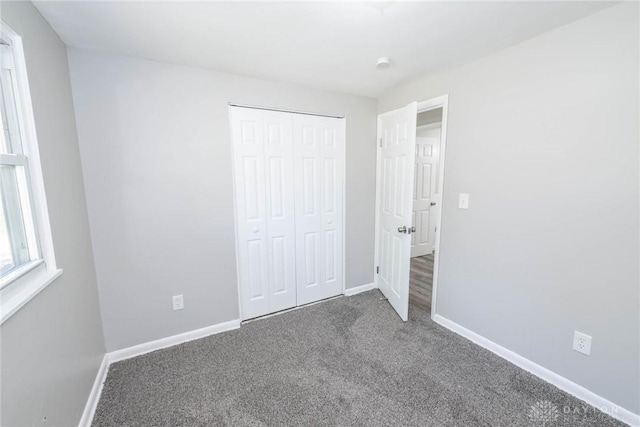 unfurnished bedroom with carpet floors, baseboards, and a closet