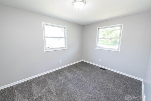 unfurnished room featuring baseboards, visible vents, and dark colored carpet