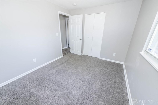 unfurnished bedroom featuring baseboards, carpet flooring, and a closet