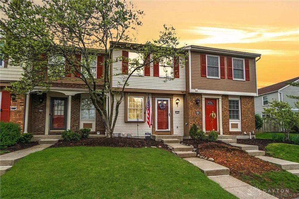 view of property with brick siding and a front yard