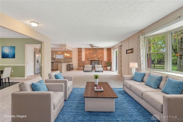 carpeted living room with a ceiling fan, baseboards, a sink, and a fireplace