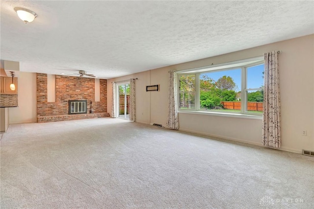 unfurnished living room featuring visible vents, a brick fireplace, carpet flooring, a textured ceiling, and a ceiling fan