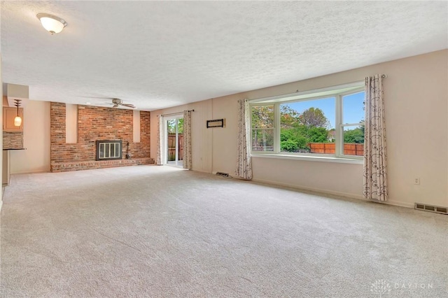 unfurnished living room featuring visible vents, a ceiling fan, a textured ceiling, and carpet flooring