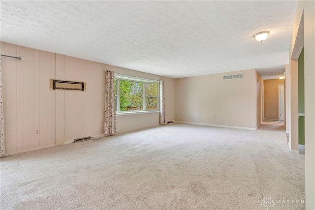 spare room featuring baseboards, carpet flooring, a textured ceiling, and visible vents