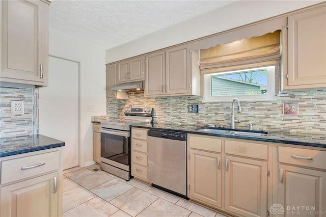 kitchen with appliances with stainless steel finishes, a sink, backsplash, light tile patterned floors, and under cabinet range hood