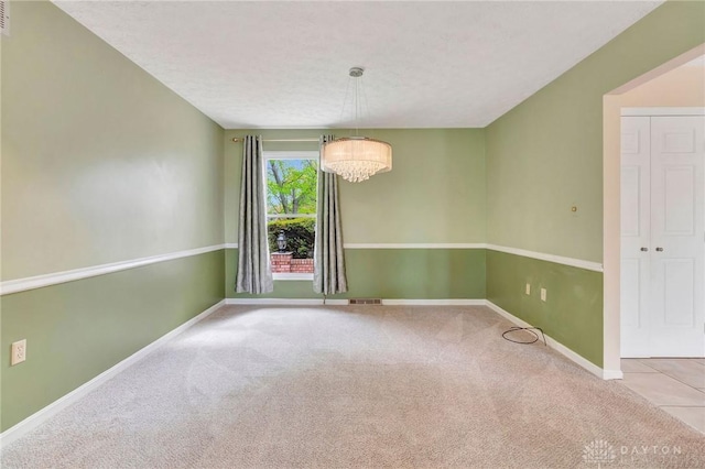empty room featuring a textured ceiling, baseboards, visible vents, and carpet