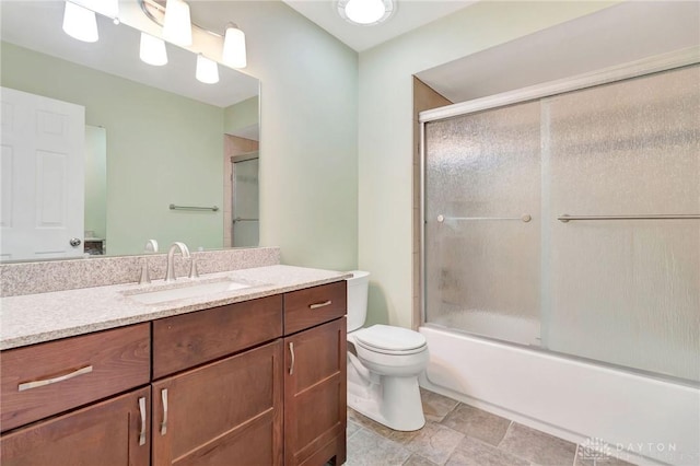 bathroom with vanity, toilet, and shower / bath combination with glass door
