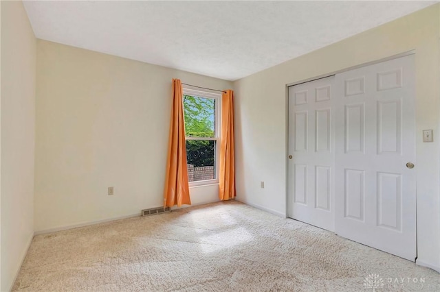 unfurnished bedroom featuring a closet, baseboards, carpet flooring, and visible vents
