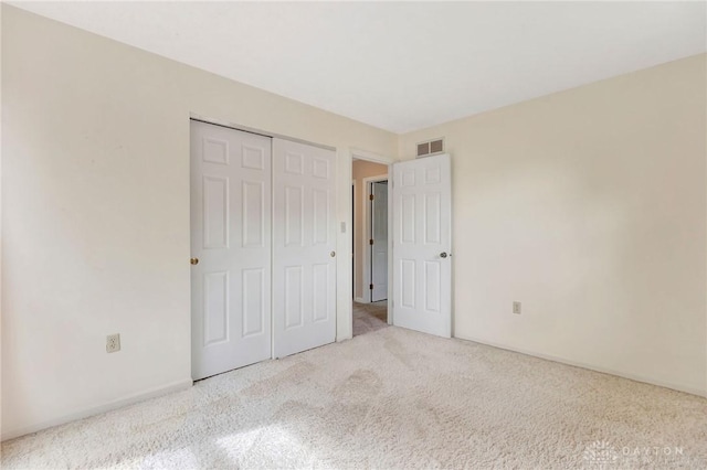 unfurnished bedroom with carpet floors, a closet, and visible vents
