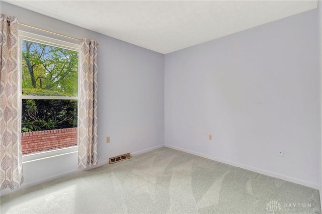 carpeted empty room with visible vents and baseboards