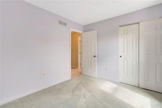 unfurnished bedroom with visible vents, carpet, baseboards, and a closet