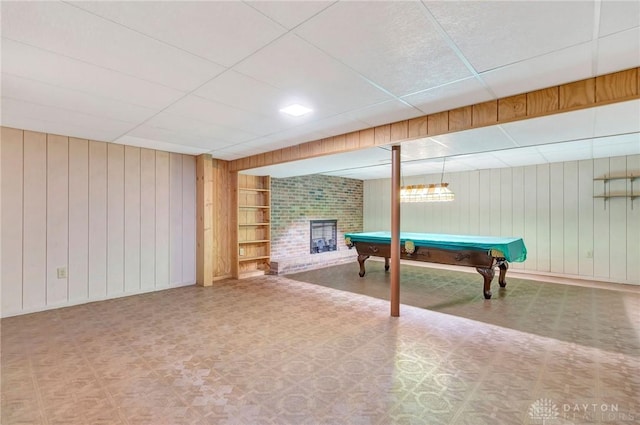rec room featuring a paneled ceiling, pool table, a fireplace, tile patterned floors, and wooden walls