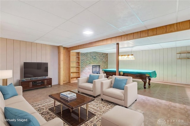 living area with a fireplace, wood walls, built in features, billiards, and a drop ceiling