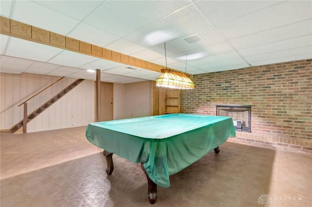 playroom featuring pool table, a drop ceiling, wood walls, and brick wall