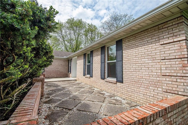 view of home's exterior featuring brick siding and a patio