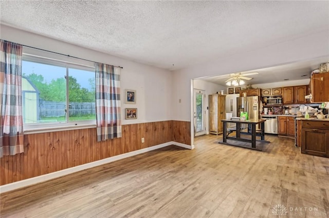 1015 Colorado Dr, Xenia, OH 45385 - living area with light wood-type flooring, a textured ceiling, a wainscoted wall, wood walls, and ceiling fan