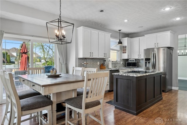 1252 Windsor Dr, Dayton, OH 45434 - kitchen with decorative backsplash, wood finished floors, white cabinets, a notable chandelier, and stainless steel appliances