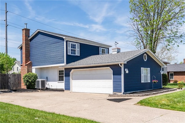 traditional-style house with a chimney, central air condition unit, fence, concrete driveway, and an attached garage