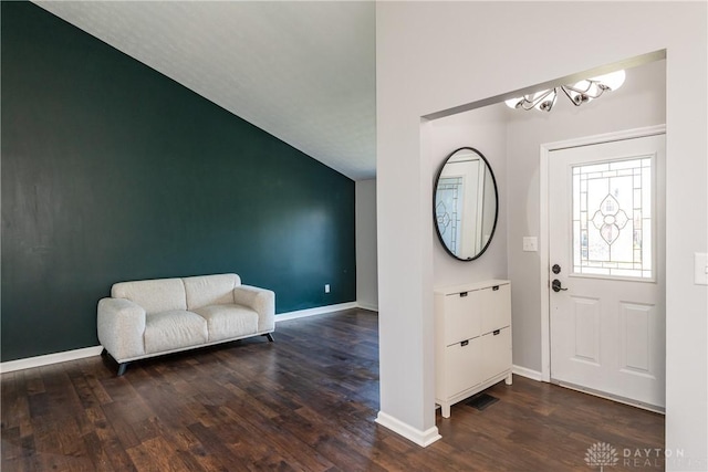 foyer entrance with baseboards, vaulted ceiling, wood finished floors, and a notable chandelier