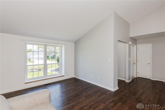 unfurnished living room featuring baseboards, vaulted ceiling, and dark wood-type flooring