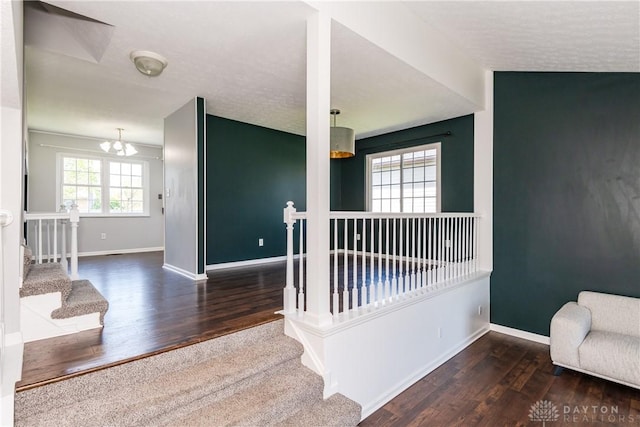 stairs with baseboards, wood finished floors, and an inviting chandelier