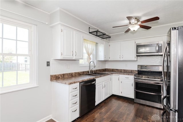 kitchen with a ceiling fan, dark countertops, dark wood-type flooring, a sink, and stainless steel appliances