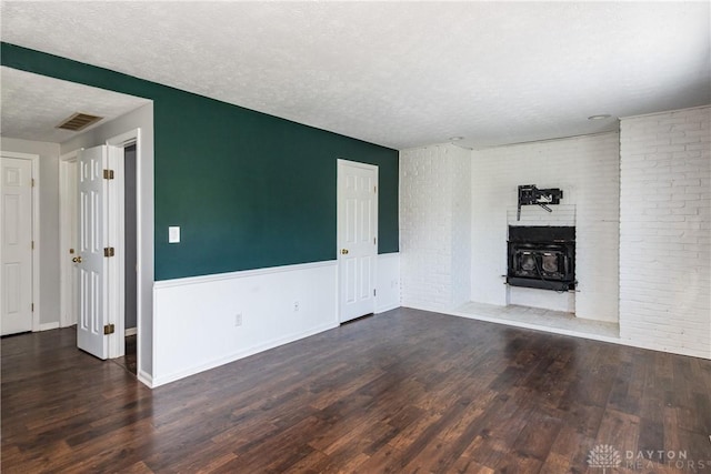 unfurnished living room featuring visible vents, a textured ceiling, wood finished floors, and brick wall