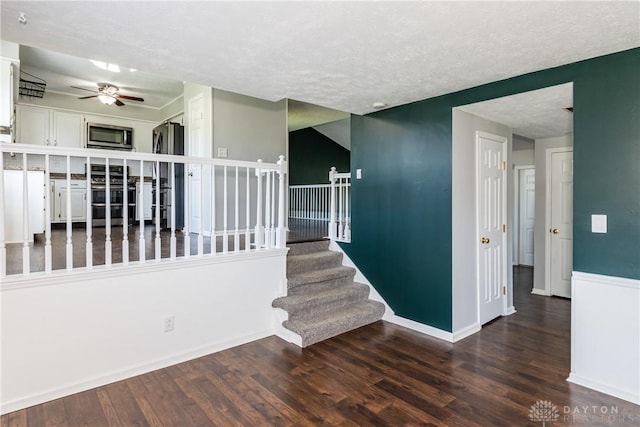 interior space featuring a ceiling fan, a textured ceiling, wood finished floors, and stairway